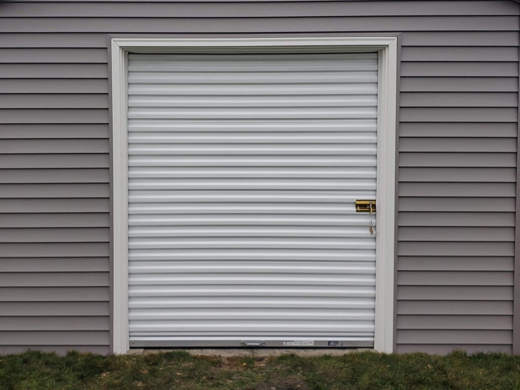 Custom shed with vinyl siding and roll up door.