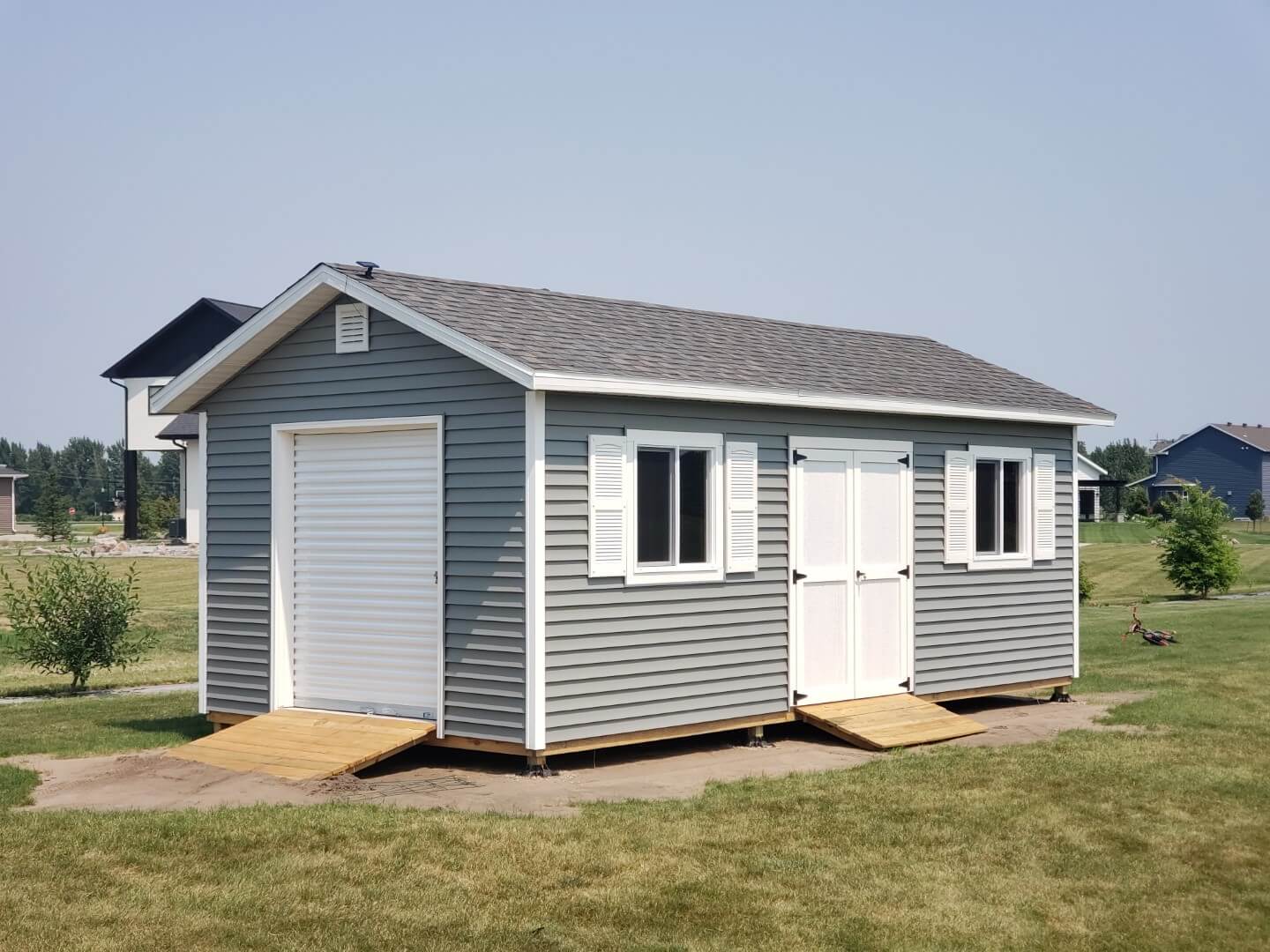 Fargo custom storage shed with vinyl siding and vented overhangs.